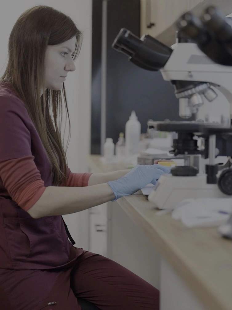 Lekarz siedzący przy mikroskopie i wykonujący badania laboratoryjne